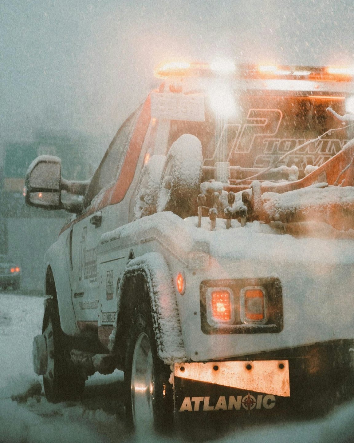 Autocarro di soccorso coperto di neve con luci lampeggianti in condizioni di foschia.